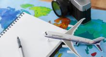 Stock photo of Plane model, camera, notebook on top of a map